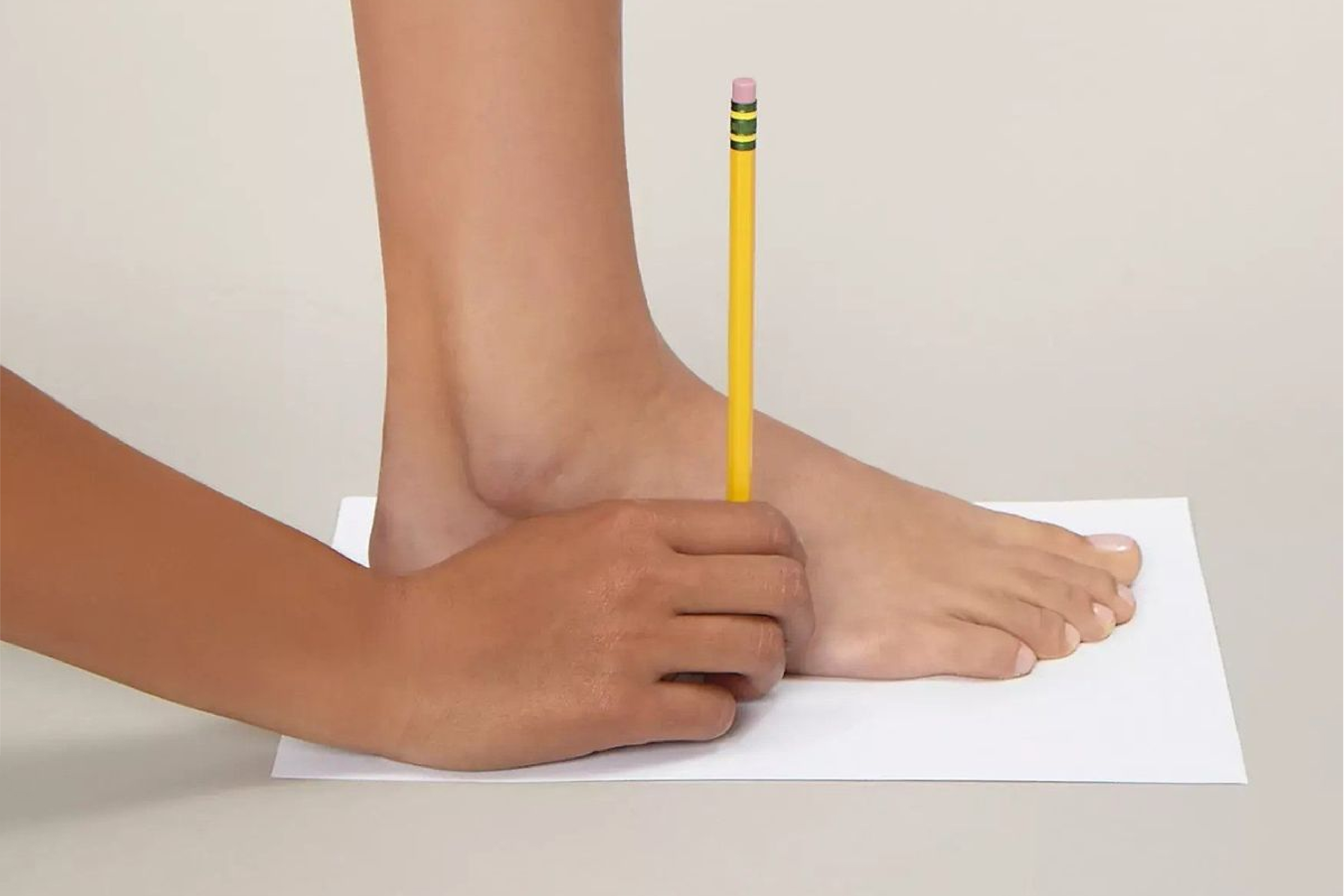 A sheet of paper, a pencil, and a ruler laid out to measure a foot at home