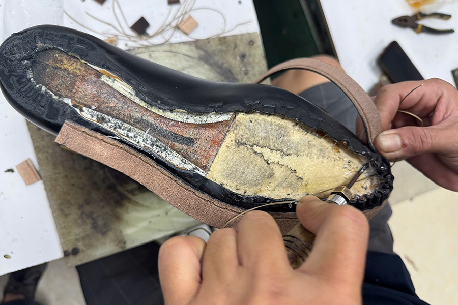 An artisan's hands stitching a Goodyear welt onto a leather shoe upper&nbsp;